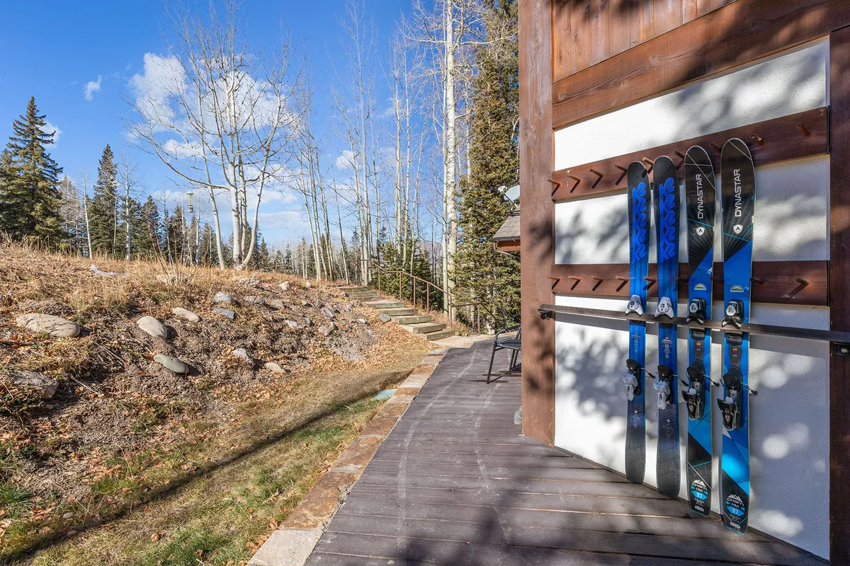 An exterior image focused on ski equipment resting on a wooden deck, set against a backdrop of natural landscape. The scene captures the adventurous spirit of Telluride, with subtle hints of both winter and summer activities.