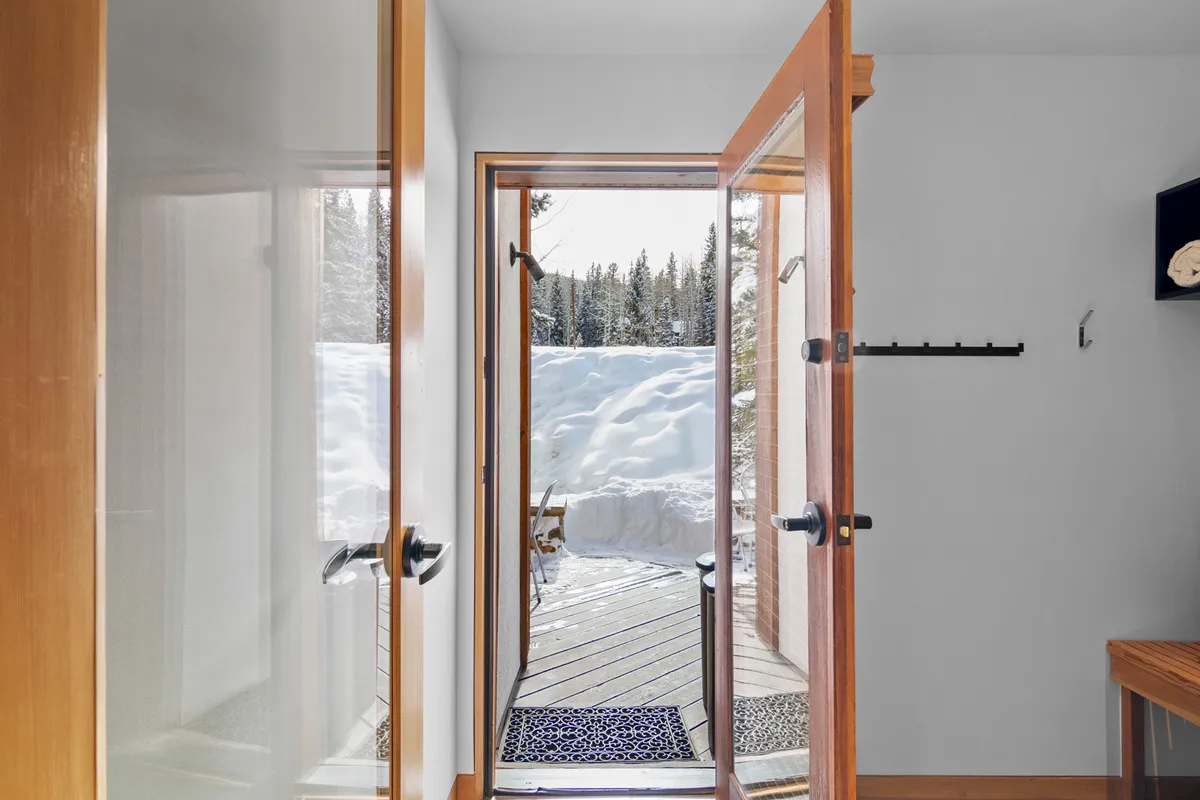 This image captures an open doorway leading into the home's entryway, with inviting entryway decor and a glimpse of the snow-covered landscape outside. The flooring and welcoming atmosphere set the tone as guests transition from the outdoors to the warmth within.